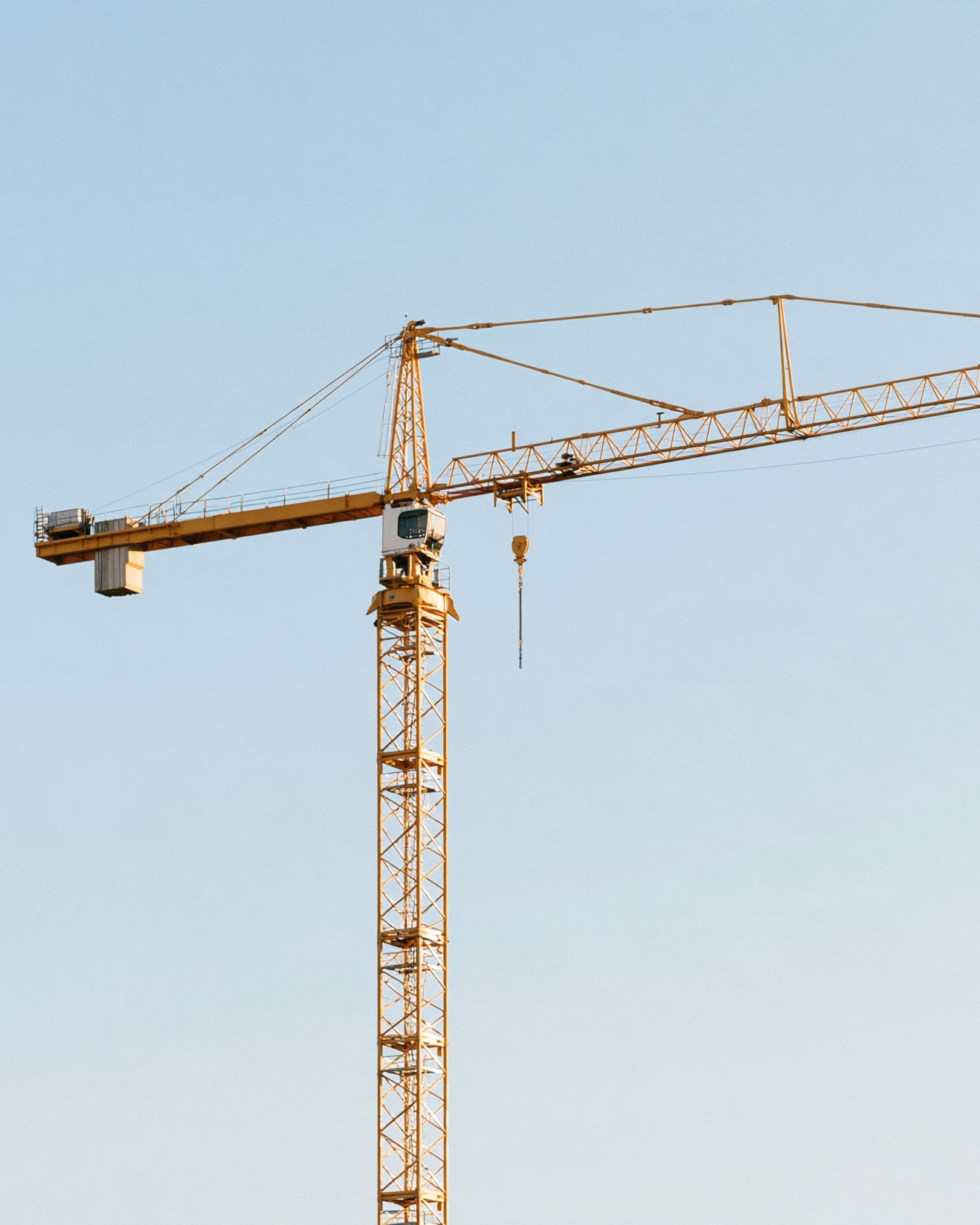 A yellow tower crane against a clear blue sky